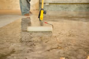 Man using a roller to clean a stained concrete